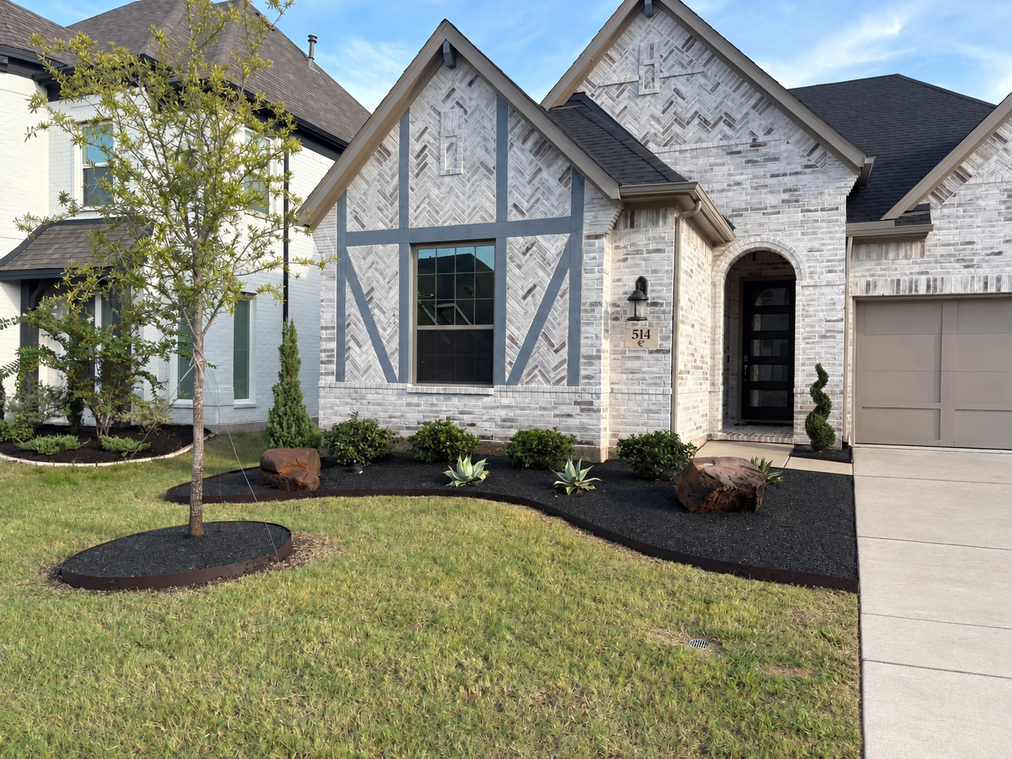 Same front yard after landscaping with dark gravel and refreshed planting