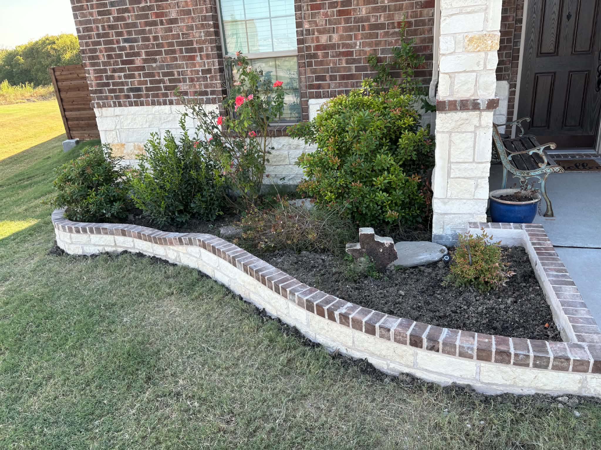 Flower bed before cleanup with overgrown shrubs