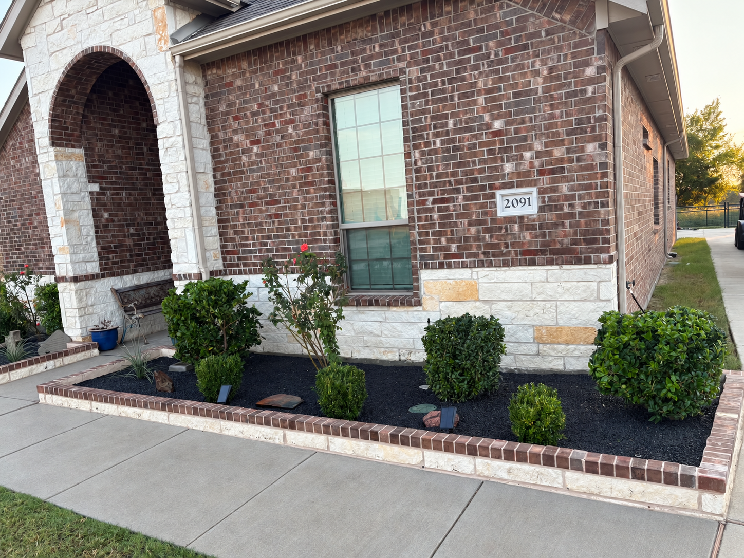 Finished flower bed with trimmed shrubs, plants and decorative black gravel